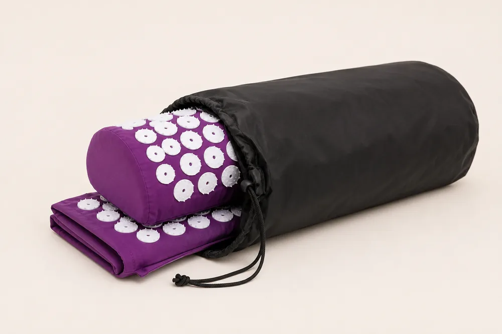 A purple SpikeRest mat and bolster rolled and half-inserted into the black drawstring carry bag, showing it fits
